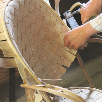 fabrication de fauteuils en châtaignier, pose du jonc sur le bord